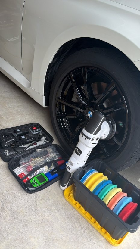 Professional cordless polisher and colorful foam pads setup by BMW wheel